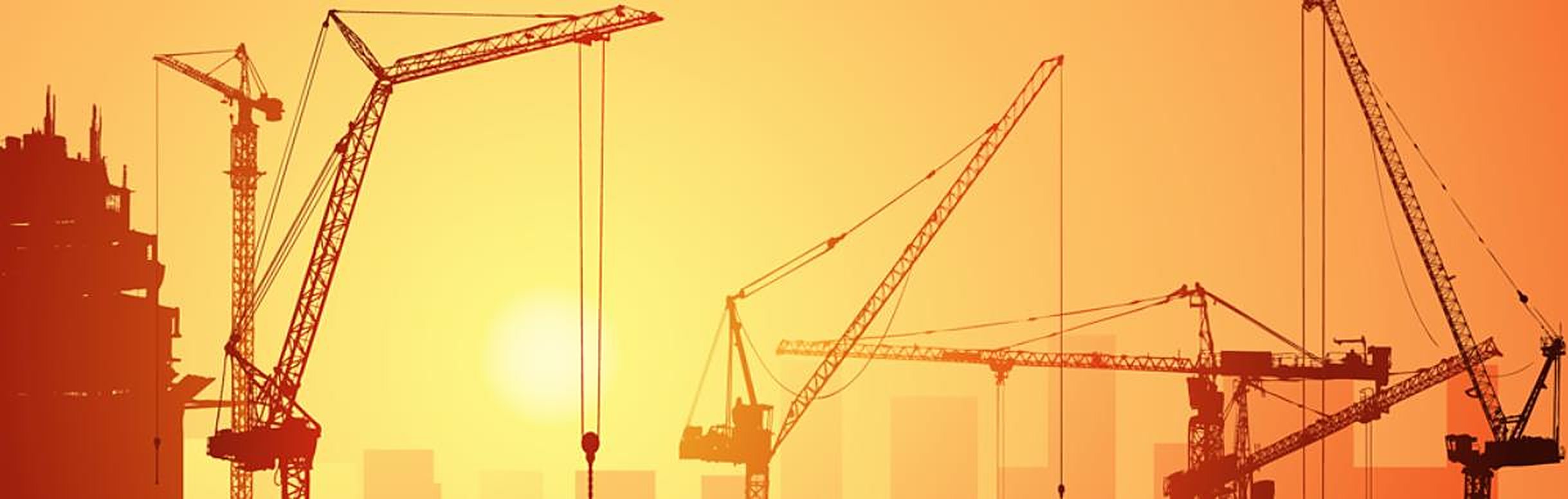 Tower cranes silhouetted against a construction site sunset